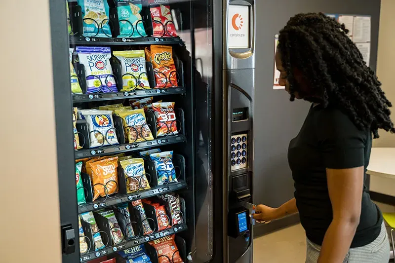 Woman paying with a card at the reader on a snack vending machine
