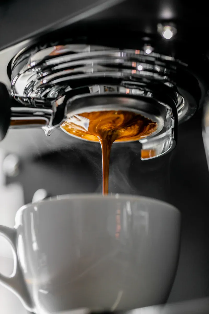Espresso pouring from a coffee machine into a white cup