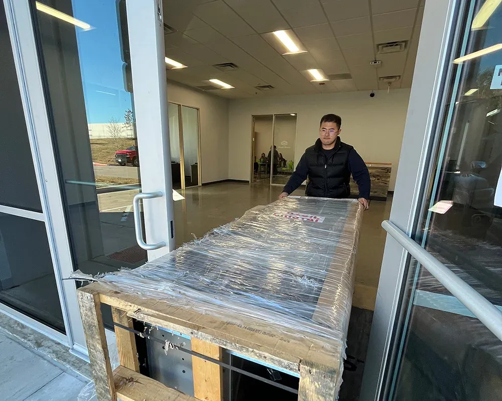 Mover guiding shrink-wrapped equipment on a pallet through a building entrance