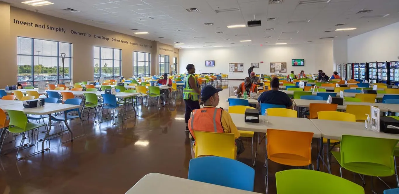 Warehouse cafeteria with workers at tables and colorful chairs