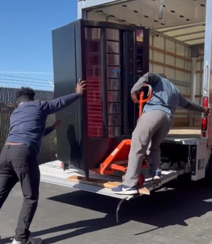 Two movers using a pallet jack to load a vending machine into a truck Texas Vending Moving Dallas Fort Worth
