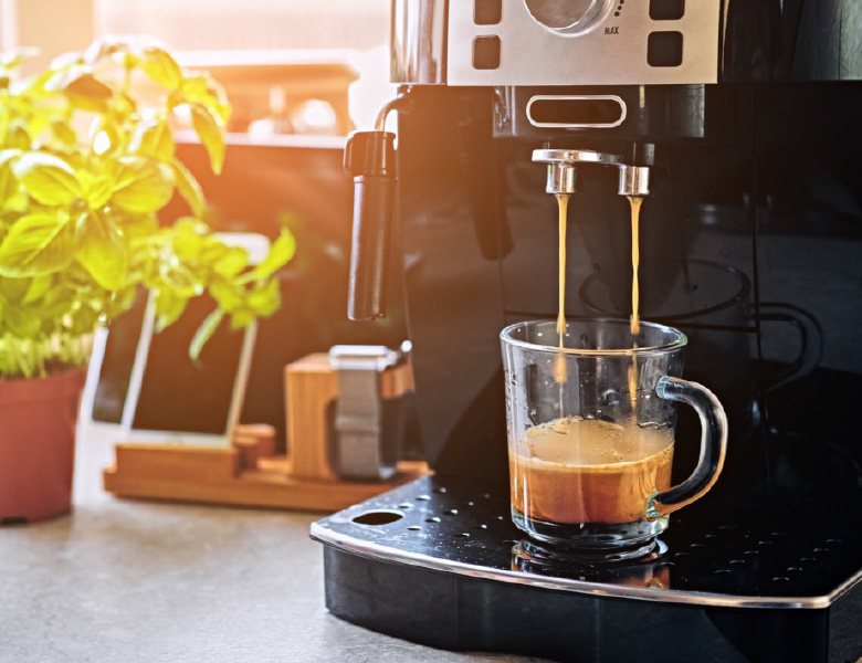 brewing a cup of espresso into a clear glass mug