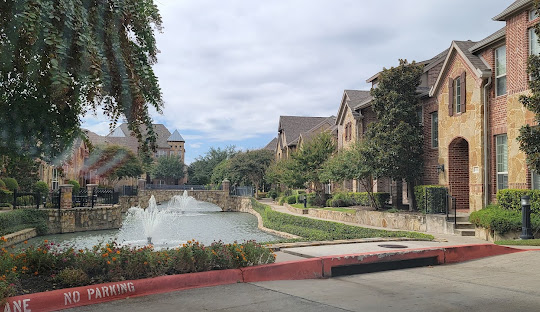 Townhomes along Chaucer Lane in Farmers Branch, Texas, featuring a central water fountain feature