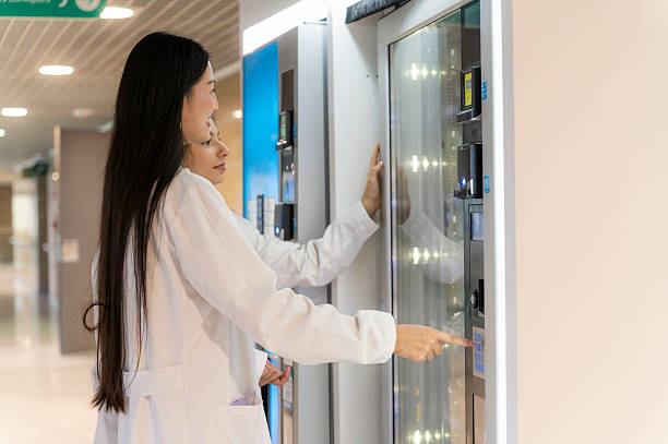 Female doctors finding refreshment from vending machine in hospital corridor at Irving Texas