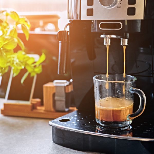 brewing a cup of espresso into a clear glass mug